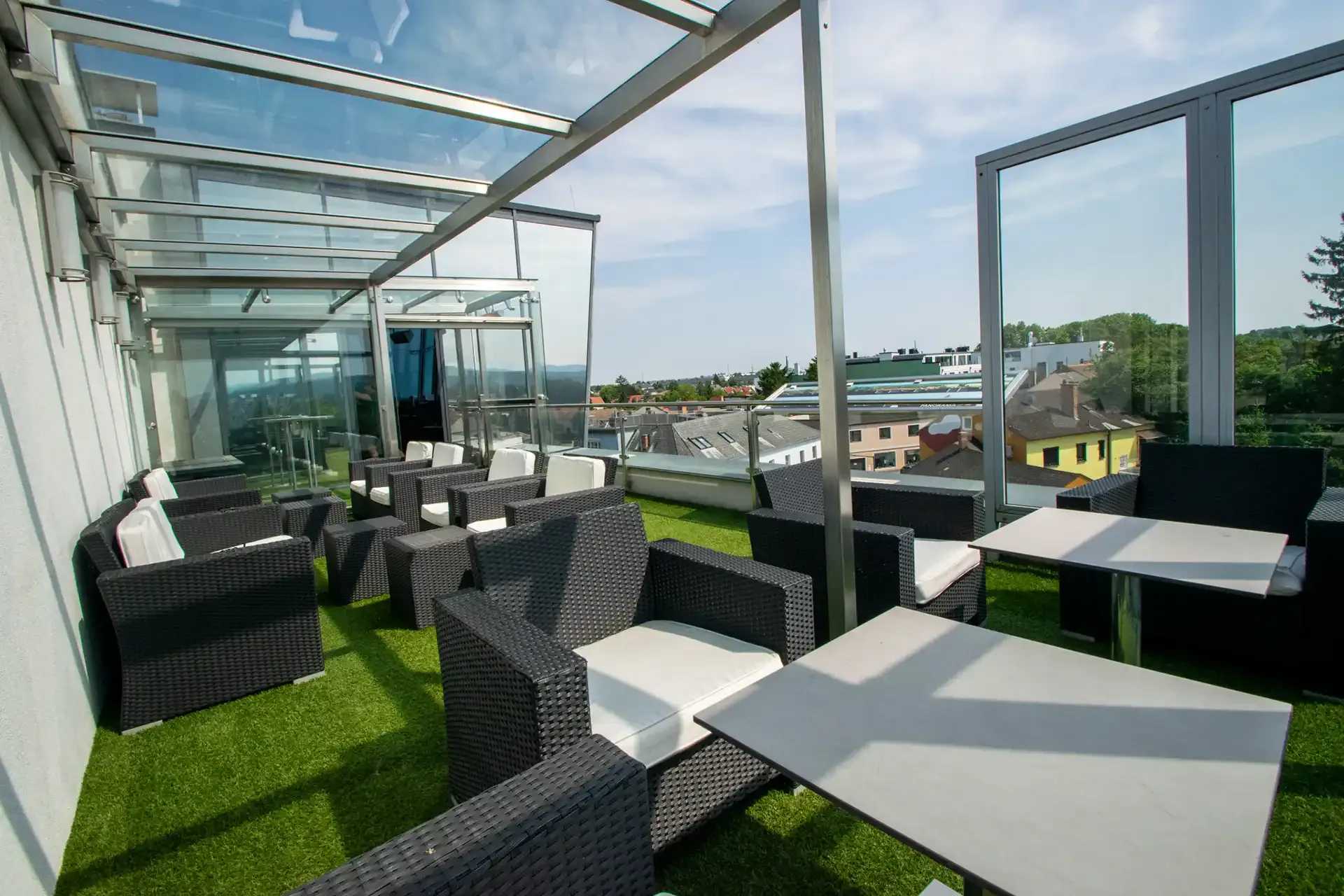Terrasse mit Lounge-Möbeln unter dem Glasdach